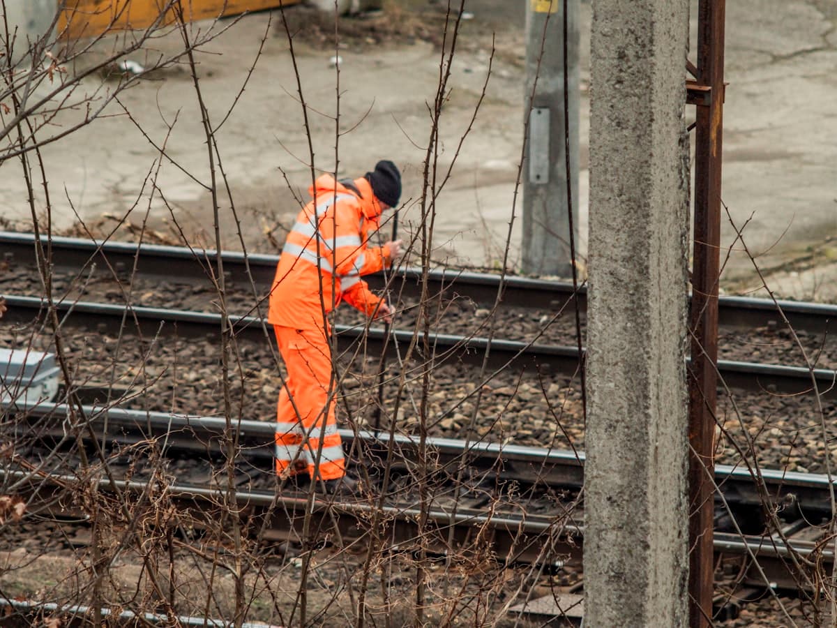 Fachkraft in Warnschutzkleidung bei Arbeiten im Gleisbereich